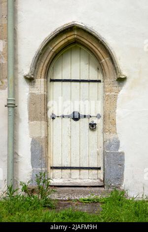 Petite porte voûtée avec porte en bois, à l'église de la Toussaint, Brandeston, Suffolk Banque D'Images