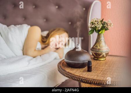 Concept d'aromathérapie. Diffuseur et humidificateur d'huile essentielle à ultrasons en bois électrique. Diffuseur d'arôme ultrasonique pour la maison. Femme se reposant à Banque D'Images