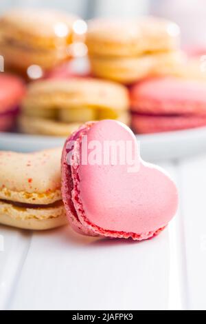 Macarons doux en forme de cœur sur une table blanche. Banque D'Images