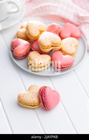 Macarons doux en forme de cœur sur une table blanche. Banque D'Images