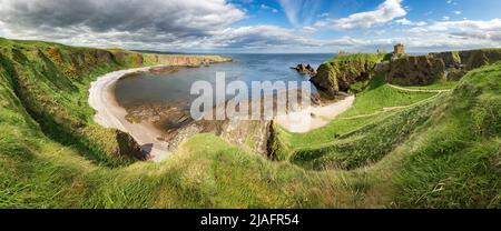 Panorama d'une falaise avec un ancien château dans une baie avec ciel bleu et nuages blancs dans le château de Dunnottar, près de Stonehaven, Aberdeenshire, Écosse - Royaume-Uni Banque D'Images