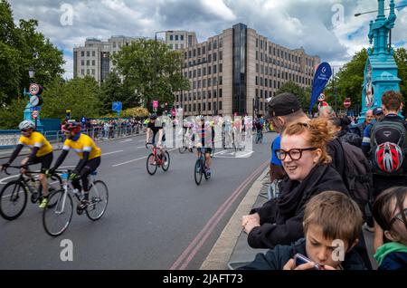 Un jeune garçon ignore ce qui se passe alors que les spectateurs regardent les cyclistes participant à RideLondon 2022 approcher de la ligne d'arrivée sur Tower Bridge à Londres. Banque D'Images