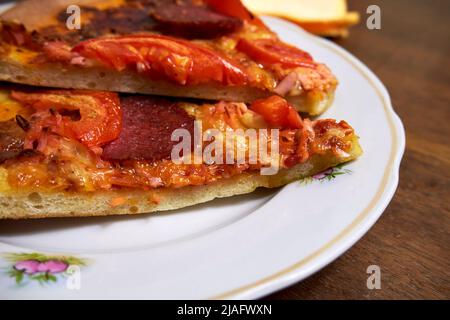 Morceaux de pizza pepperoni sur une assiette blanche vue rapprochée Banque D'Images