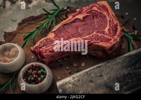 concept alimentaire de steak de bœuf cru avec romarin, sel et poivre et couteau à laver sur la planche à découper en bois Banque D'Images