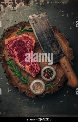 vue de dessus de viande rouge sanglante avec sel et poivre et couteau à laver sur planche à découper en bois Banque D'Images