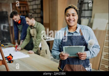 À la taille, portrait de menuisier femme tenant le presse-papiers et regardant la caméra tout en posant dans un atelier d'artisanat, espace de copie Banque D'Images