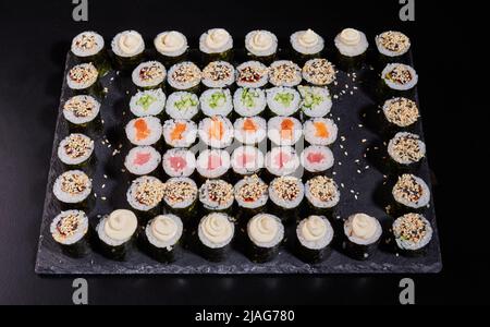Sushi japonais. Différents types de rouleaux maki sur une plaque sur fond de pierre. Banque D'Images