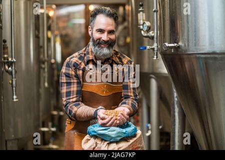 Maître brasseur examinant les graines d'orge avant qu'elles entrent en production. Technicien de brasserie avec sac d'orge devant. Banque D'Images