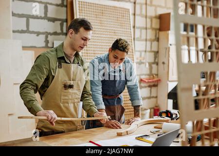 Portrait aux tons chauds de deux menuisiers qui conçoivent des meubles faits à la main dans un atelier Banque D'Images