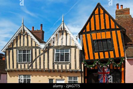 Vue sur deux bâtiments médiévaux à pans de bois, dont la Crooked House de couleur orange dans la High Street à Lavenham, Suffolk, Angleterre, Royaume-Uni. Banque D'Images