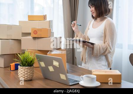 Les femmes asiatiques comptent des boîtes avant d'expédier à leurs clients, de travailler à domicile, les propriétaires de petites entreprises ou les entrepreneurs de petites entreprises commencent tout juste à travailler Banque D'Images