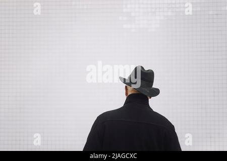 Vue arrière de l'homme âgé portant un chapeau devant le mur blanc Banque D'Images