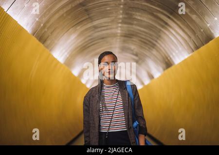 Portrait d'une jeune femme souriante aux cheveux tressés debout dans le tunnel du métro Banque D'Images