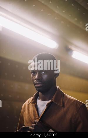 Portrait d'un jeune homme debout dans un tunnel éclairé Banque D'Images