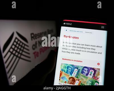 Personne tenant un smartphone avec la page Web de la banque centrale RBNZ (Reserve Bank of New Zealand) à l'écran avec le logo. Concentrez-vous sur le centre de l'écran du téléphone. Banque D'Images