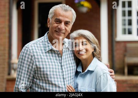 Portrait Of Mature Couple debout dans un jardin en face de maison de rêve en campagne Banque D'Images