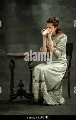 Portrait conceptuel de la jeune fille charmante à l'image de la personne royale médiévale ou de la viscomtesse pleurant isolée sur fond sombre. Comparaison des époques Banque D'Images