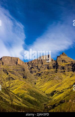 Les hautes falaises escarpées des montagnes du Drakensberg, avec de la neige en fin de saison encore légèrement visible et des nuages de haute altitude formant une forme en V. Banque D'Images