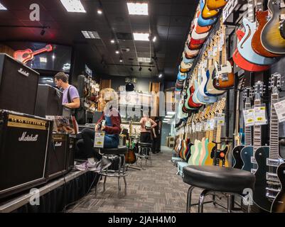 Lynnwood, WA USA - vers mai 2022: Vue d'une famille shopping pour guitares à l'intérieur d'un centre de guitare. Banque D'Images