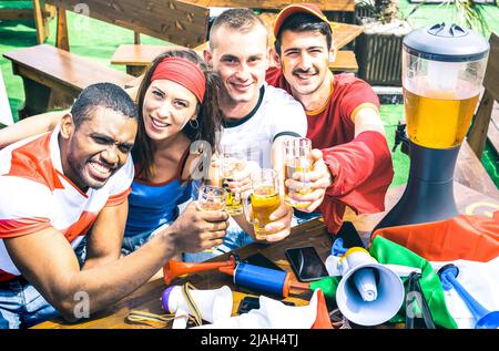 Les jeunes fans de football amateurs de bière en train de jouer à la télévision - amis personnes avec des t-shirts et drapeaux multicolores s'amuser - Sport champion Banque D'Images