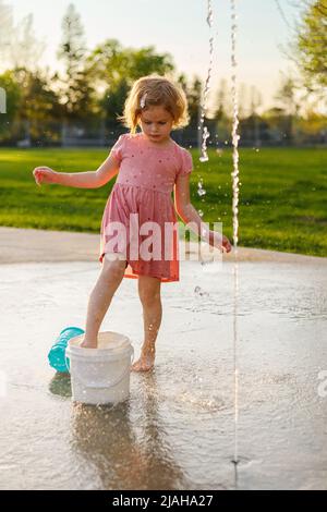 Petite fille jouant dans le parc avec des fontaines en été petit enfant s'amusant à l'aire de jeux Banque D'Images