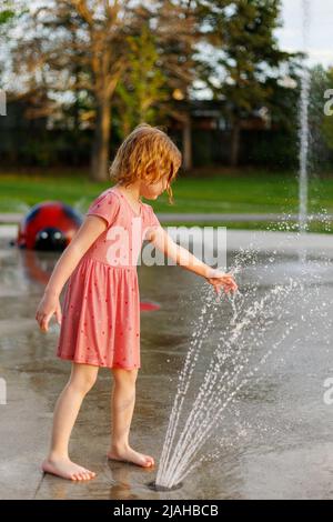 Enfants jouant avec de l'eau au terrain de jeux de l'aire de jeux du parc. Fille s'amusant avec la fontaine Banque D'Images