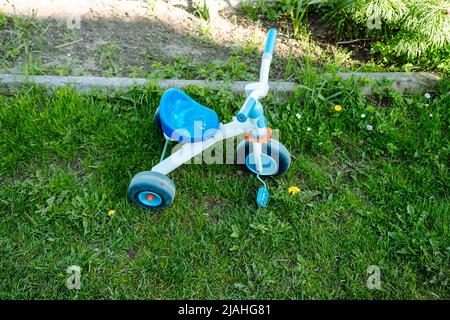 un tricycle en plastique pour enfants laissé dans la cour sur la pelouse. Banque D'Images