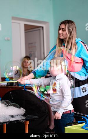 Dolyna, Ukraine 28 mai 2021: Animateurs et bulles de savon pour des vacances d'enfants, un garçon faisant une grosse bulle à lui seul, un spectacle amusant et divertissant. Banque D'Images