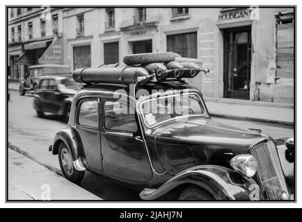 Après la guerre WW2 voiture carburant bouteille d'essence alternative. Rationnement France trafic parisien, Printemps 1945- la vie quotidienne dans l'après-guerre Paris, France, 1945 Une vue d'une rue de Paris, montrant une voiture qui a été convertie pour fonctionner à essence, plutôt que de l'essence qui est strictement rationné. Il y a quatre bouteilles de gaz fixées au toit de la voiture, et un petit tube passe sur le côté de la voiture et sous le capot. Date 1945 Banque D'Images