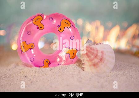 Cercle de natation décoratif avec coquillages près de lui, séjour dans le concept sable.Summertime. Banque D'Images