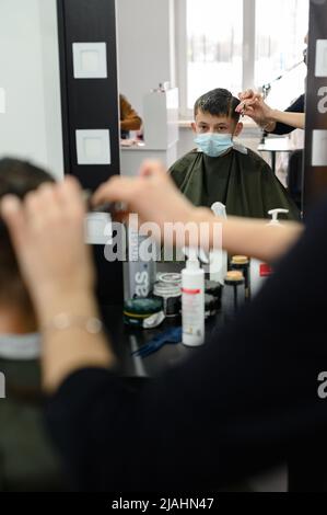 Dolyna, Ukraine 3 février 2022: Visite au coiffeur, coupe de cheveux pour enfants, coiffeurs en Ukraine pendant la quarantaine, coiffeur élégant. Banque D'Images