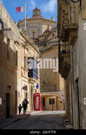 Vue depuis une rue arrière de Zurrieq jusqu'à l'église et le poste de police avec un ancien kiosque téléphonique de style britannique, Malte Banque D'Images