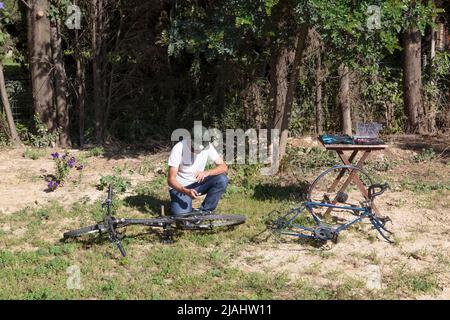 Jeune homme répare une roue de vélo dans l'arrière-cour Banque D'Images