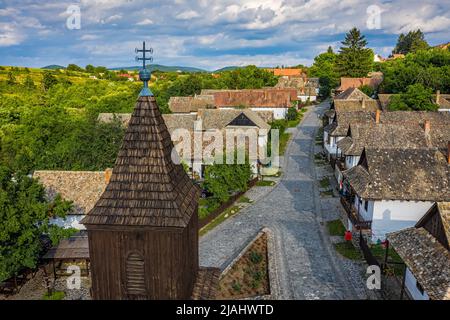 Holloko, Hongrie - vue aérienne de la tour de l'église catholique traditionnelle de Holloko au centre du village, un site de l'UNESCO en Hongrie sur un soleil Banque D'Images