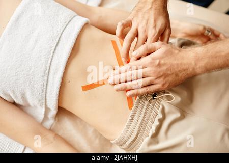 Vue de haut en bas de la réadaptation thérapeute mettant la bande physio sur les muscles de l'abdomen de la jeune femme, l'espace de copie Banque D'Images