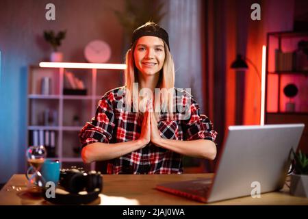 Femme agréable méditant avec les yeux fermés tout en s'asseyant au bureau avec un ordinateur portable moderne. Femme indépendante pratiquant le yoga pour soulager le stress au travail. Concept de personnes et de pensée positive. Banque D'Images