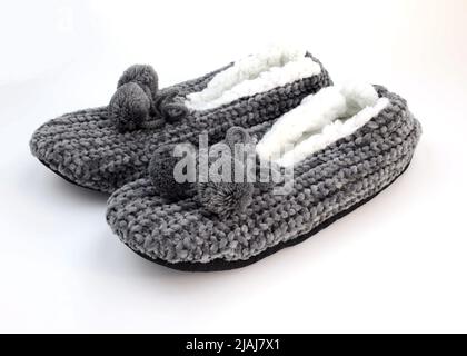 Home hiver chaussons femmes sur fond blanc. Paire de chaussures molletonnées maison en polaire avec pompons. Pantoufles douces et fermées, avec un chiffon gris Banque D'Images