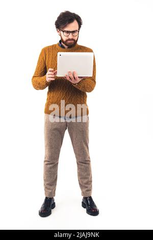 Photo en studio vertical d'un homme d'affaires indépendant élégant debout et tenant son ordinateur portable. Concept de travail. Photo de haute qualité Banque D'Images