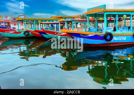 Bateaux d'excursion passagers alignés sur le front de mer à Hoi an, VN. Réflexions dans l'eau avec image déformée des bateaux. Banque D'Images