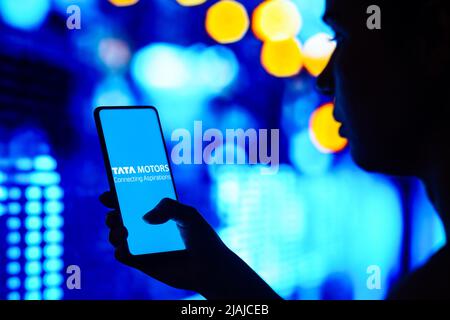 Dans cette illustration, une femme silhouetée tient un smartphone avec le logo de Tata Motors Limited affiché à l'écran. Banque D'Images