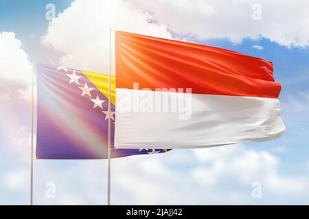 Ciel bleu ensoleillé et drapeaux de l'indonésie et de la bosnie Banque D'Images