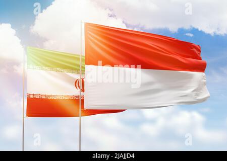 Ciel bleu ensoleillé et drapeaux de l'indonésie et de l'iran Banque D'Images