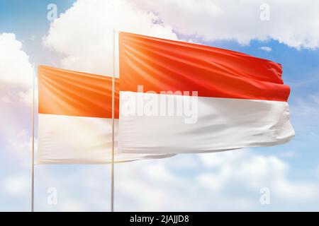 Ciel bleu ensoleillé et drapeaux de l'indonésie et de l'indonésie Banque D'Images