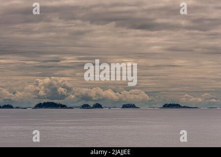 Côte du Pacifique, Alaska, États-Unis - 16 juillet 2011 : petites îles forestières vertes sous un paysage épais de nuages gris-blanc le long de la côte dans l'oc du Pacifique gris plat Banque D'Images