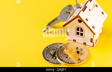 Acheter de l'immobilier pour la crypto-monnaie. Logement et bitcoins. Pièces de monnaie et clés de maison. Petite maison en bois et pièce de monnaie en bitcoin. Banque D'Images