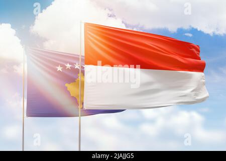 Ciel bleu ensoleillé et drapeaux de l'indonésie et du kosovo Banque D'Images