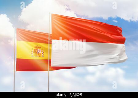 Ciel bleu ensoleillé et drapeaux de l'indonésie et de l'espagne Banque D'Images