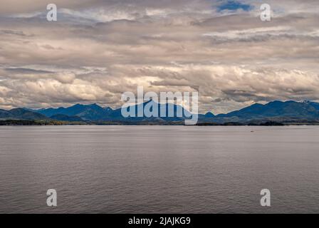 Côte du Pacifique, Alaska, États-Unis - 16 juillet 2011: Quelques petites îles forestières vertes sous un paysage de nuages gris-blanc lourd le long de la côte montagneuse dans la Fla Banque D'Images