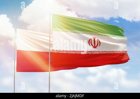 Ciel bleu ensoleillé et drapeaux de l'iran et de la pologne Banque D'Images