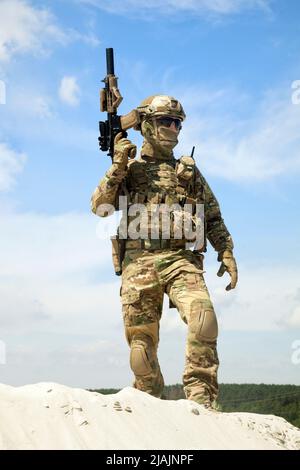 Soldat debout sur une dune de sable avec une carabine de service entre les mains. Banque D'Images